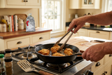 Frying battered chicken in a skillet with Yard Bird Batta nearby.